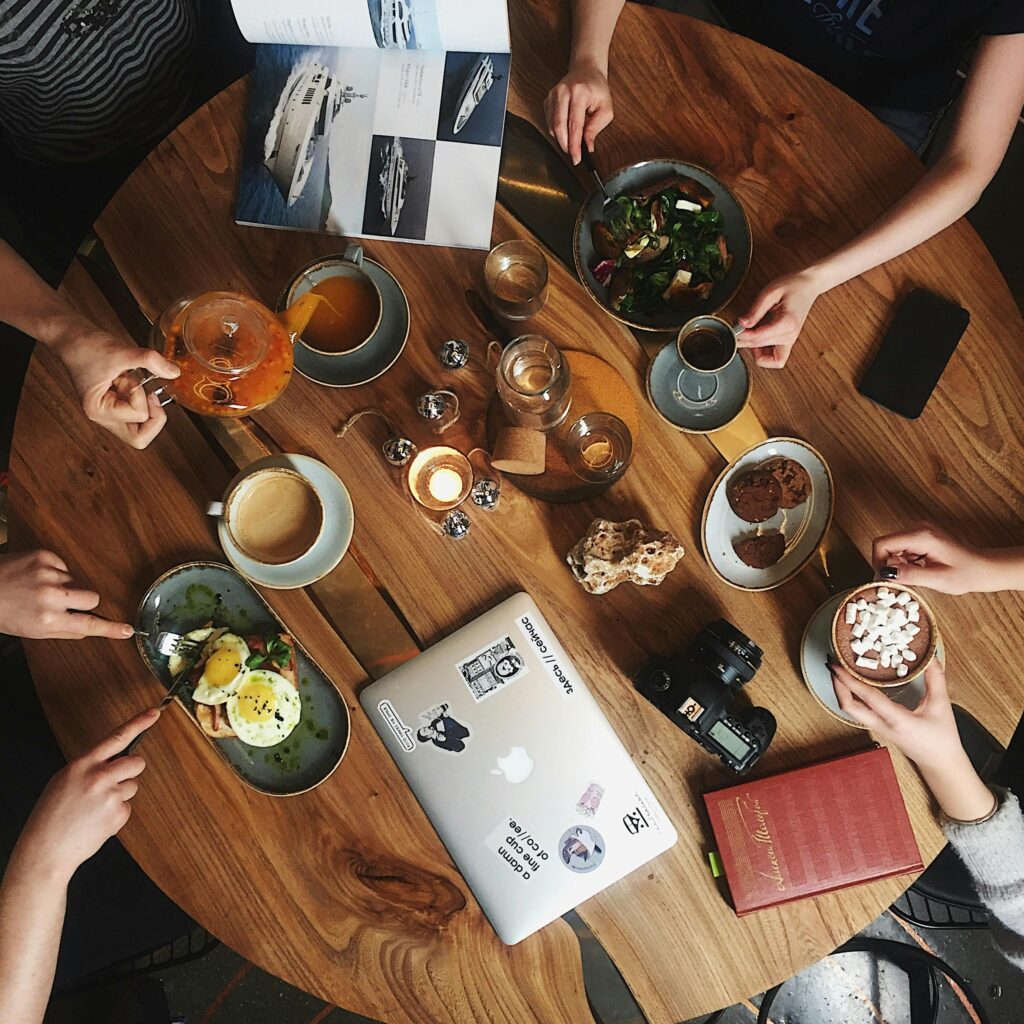 pexels-photo-2130137-2130137 Overhead view of a cozy cafe setting with drinks, laptops, and books, perfect for teamwork or relaxation.
